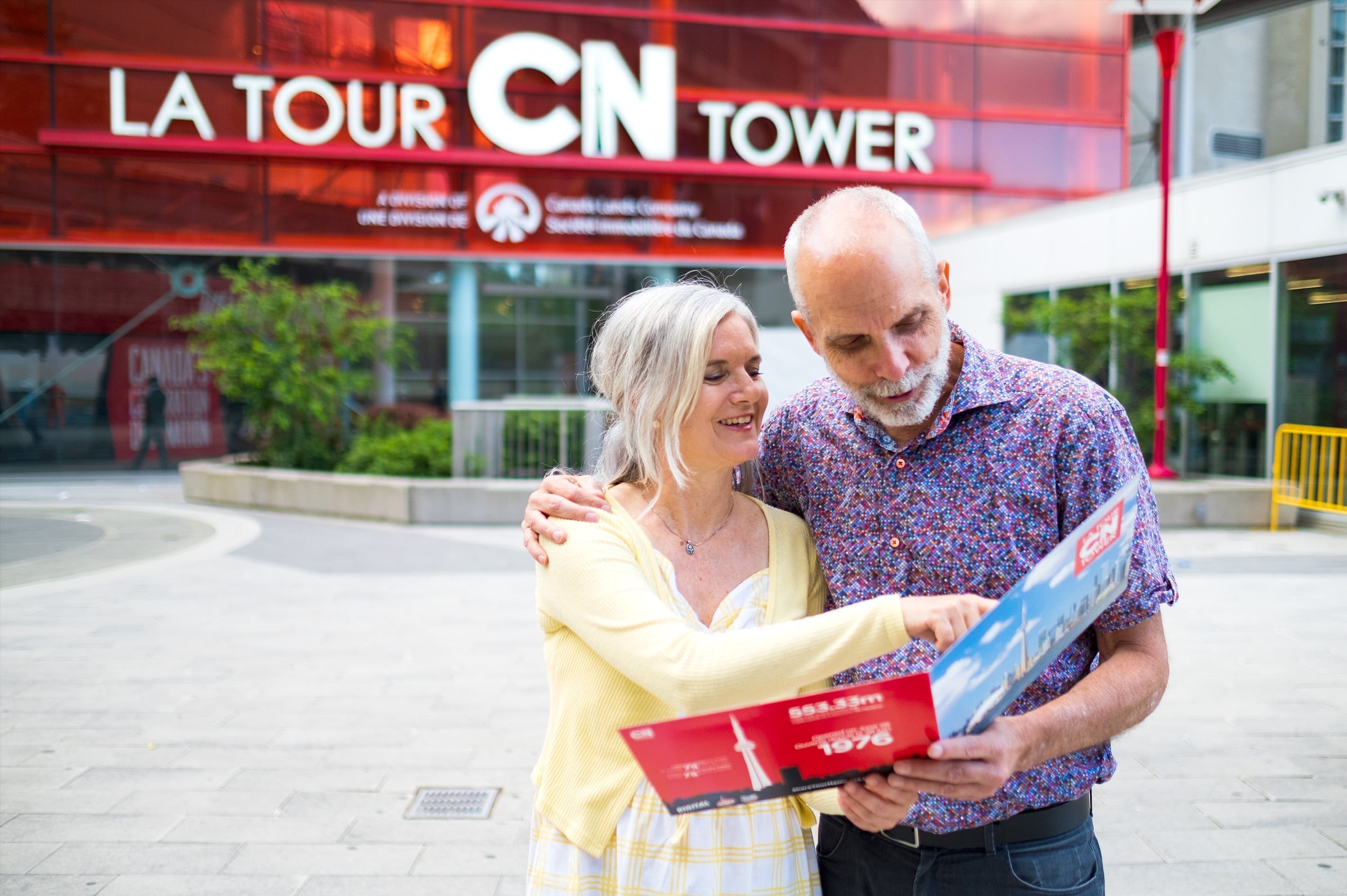 Un couple regarde sa photo-souvenir devant la Tour CN